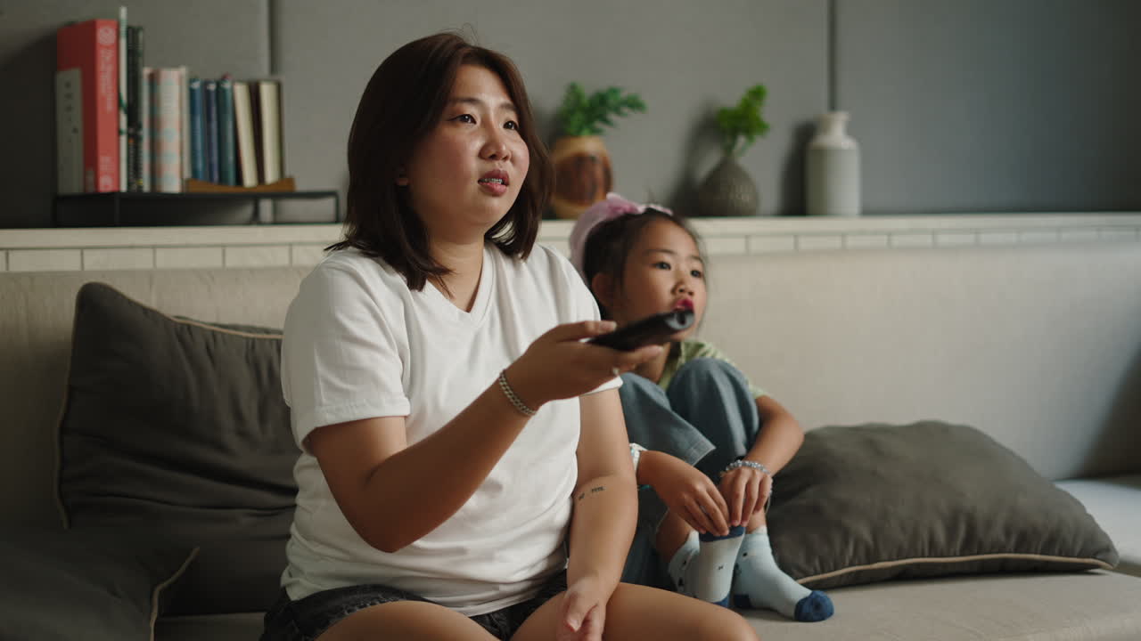 Madre e figlia asiatiche che guardano la televisione insieme a casa