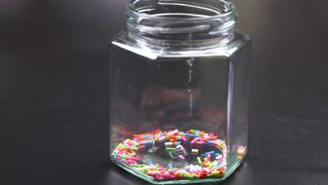 pouring sprinkles into a glass jar