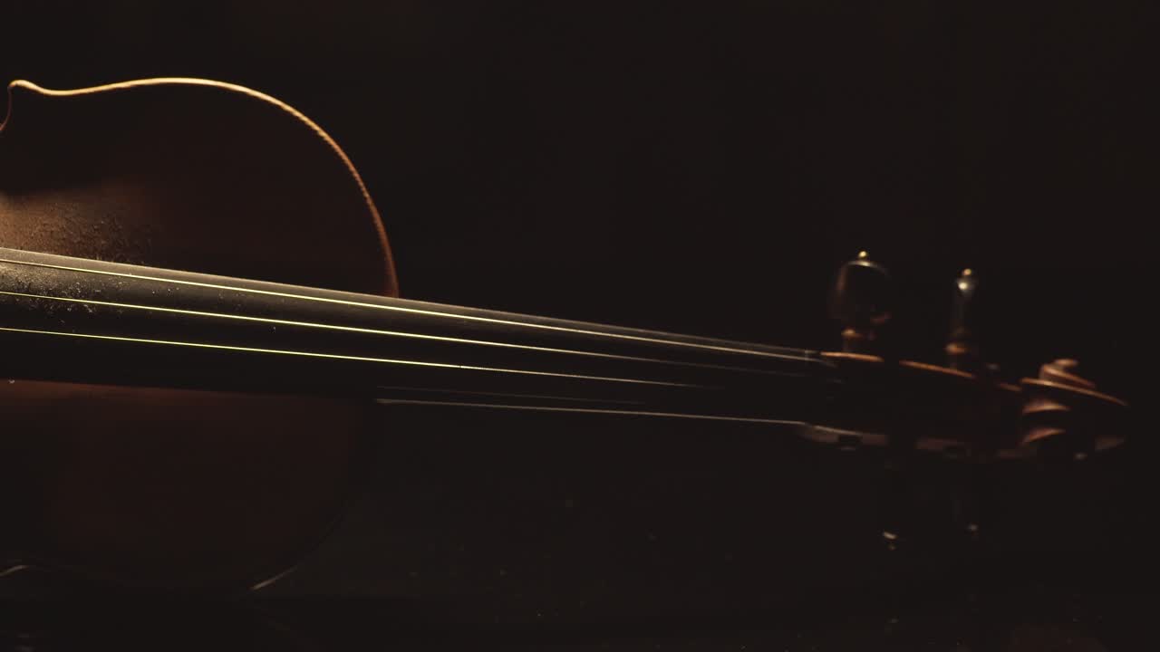 古小提琴的近景, 樂器上的劇烈光線變化, 經典交響曲音樂視頻片段