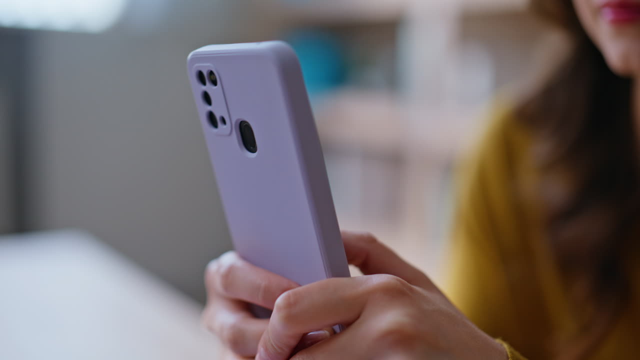 Hands scrolling news feed at mobile phone sitting apartment interior closeup