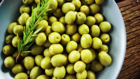 fresh green olives and rosemary in a bowl