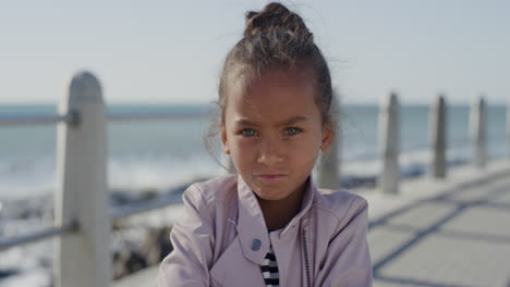 portrait angry little girl arms crossed looking serious naughty child on sunny seaside beach slow motion