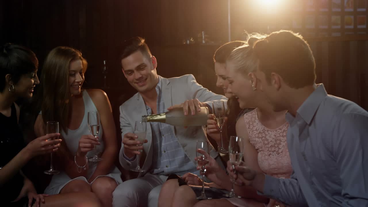 Man pouring champagne for group toasting at events, animated red hearts overlaying and drifting