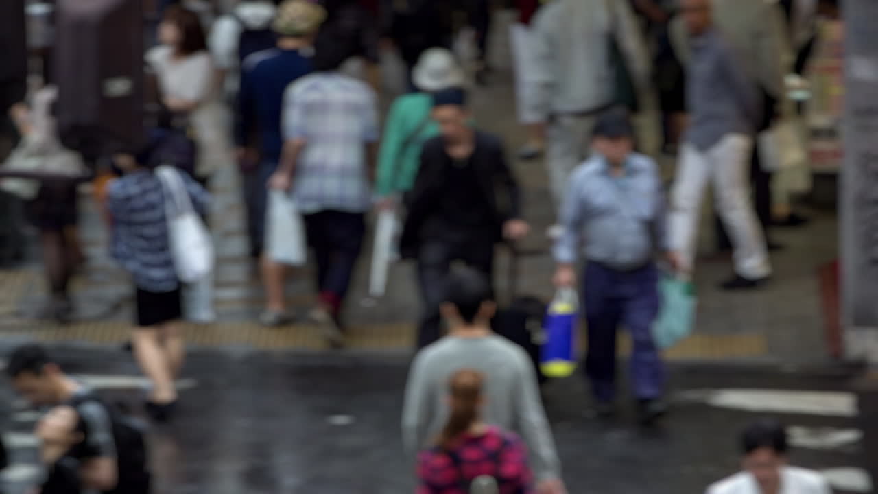 A blurry image of a crowded street with many people walking