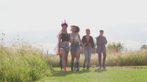 group of excited young female friends walking through music festival site