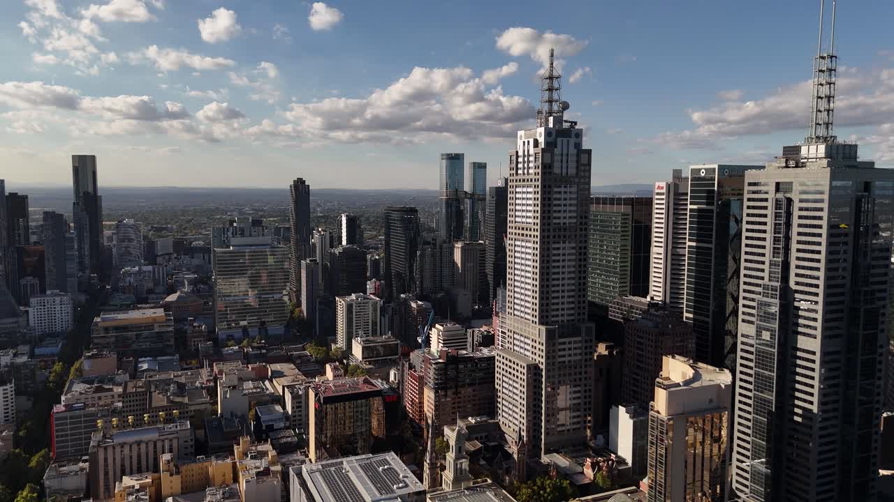 Aerial view of a bustling city skyline with numerous skyscrapers under a partly cloudy sky
