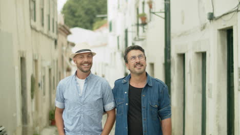 front view of gay couple walking narrow city streets on date