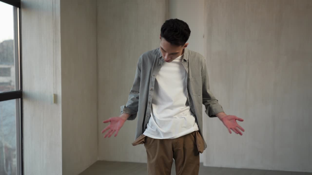 아시아인 남자가 빈 주머니에 손을 넣고 돈을 찾습니다.