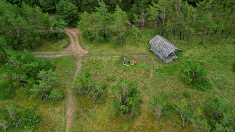 small wooden cabin home in rural landscape near forest, aerial drone view