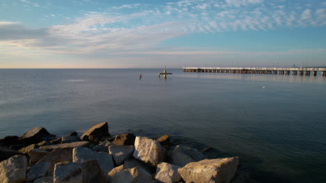 Orlowo-Pier-and-Rocky-Sandy-Beach-on-Sunrise-in-Gdynia,-Poland---Aerial-Push-Back-Revealing