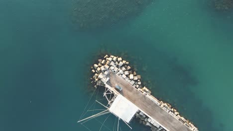 Aerial-top-view-of-a-trabucco,-traditional-fishing-machine,-on-the-italian-seashore,-at-sunset