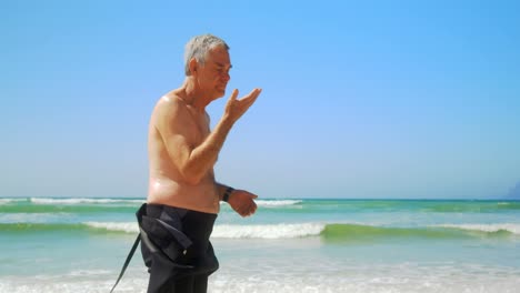 Seitenansicht-Eines-Aktiven-älteren-Kaukasischen-Männlichen-Surfers,-Der-Am-Strand-Steht-4k