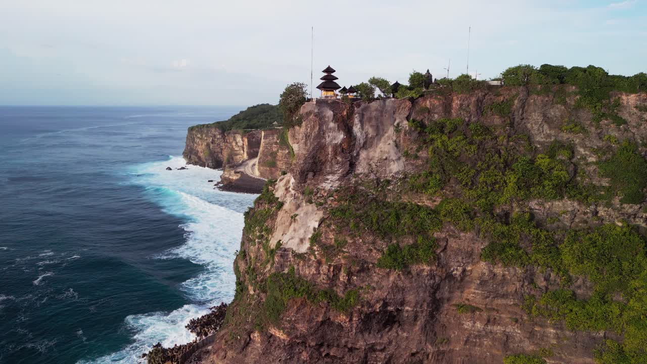 Cinematic drone shot of Uluwatu Temple standing high above the coastline, with dramatic cliffs and powerful waves highlighting the islands rich scenery and strong connection to Balinese heritage