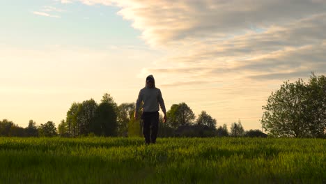 Landwirt-Spaziert-Während-Des-Idyllischen-Sonnenuntergangs-Zur-Goldenen-Stunde-Auf-Einem-Grünen-Weizenfeld,-Lettland