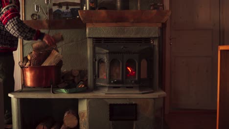 Man-In-The-House-Stacking-Firewood-Next-To-Cast-Iron-Wood-Burning-Stove