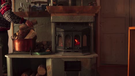 man in the house stacking firewood next to cast iron wood burning stove