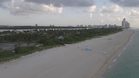 Luftaufnahmen-Im-Frühen-Morgengrauen-Vom-Leeren-Haulover-Strand-Und-Einer-Reihe-Von-Rettungsschwimmertürmen