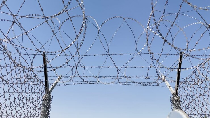 Filo spinato all'uscita del cancello della prigione | Lento movimento verso l'apertura mentre gli uccelli volano