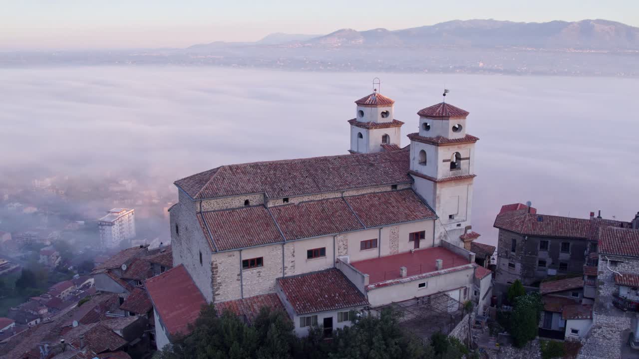 Luce dell'alba sulla Chiesa di Santo Stefano tra colline nebbiose ad Artena, Italia