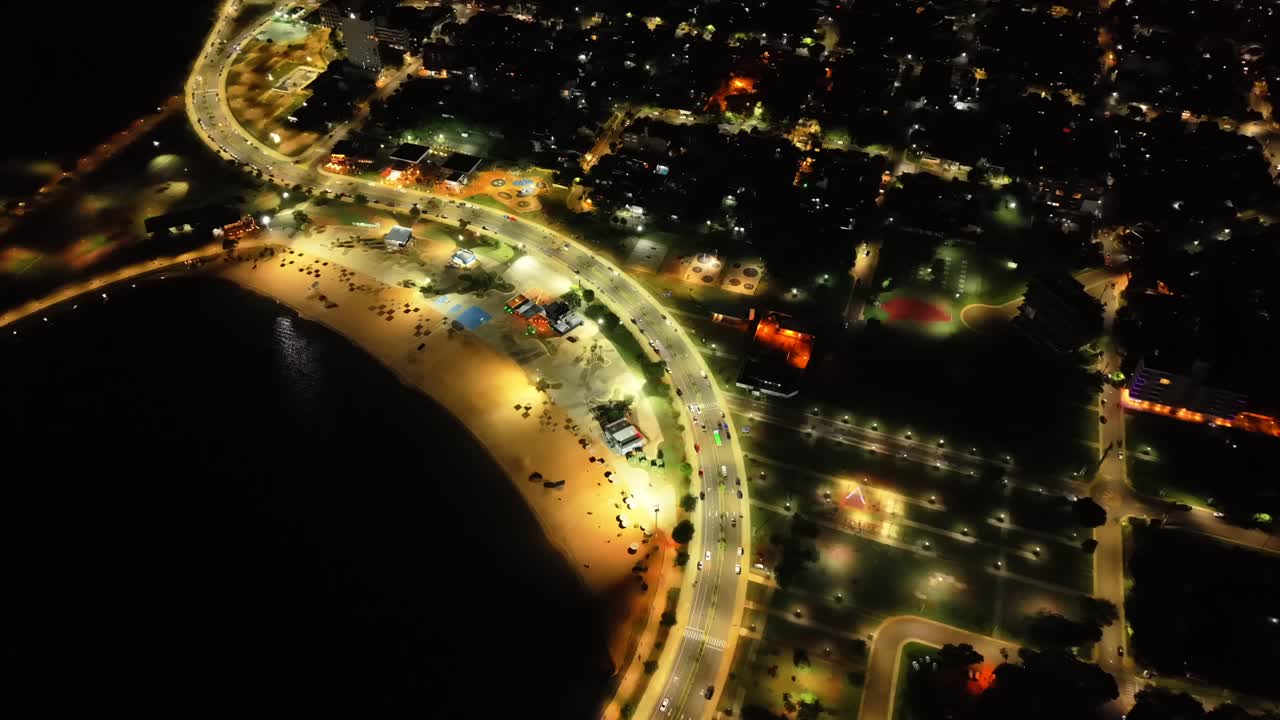 Approaching aerial movement of beachside Costanera's Roundabout with park lights at night in Posadas, Misiones, Argentina.