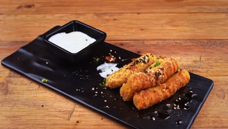 Close-up-of-a-plate-of-breaded-cheese-fingers-with-sesame-seeds,-habanero-peppers,-ranch-dressing-and-Worcestershire-sauce,-cheese-finger-dipped-in-ranch-dressing,-being-removed-from-the-plate