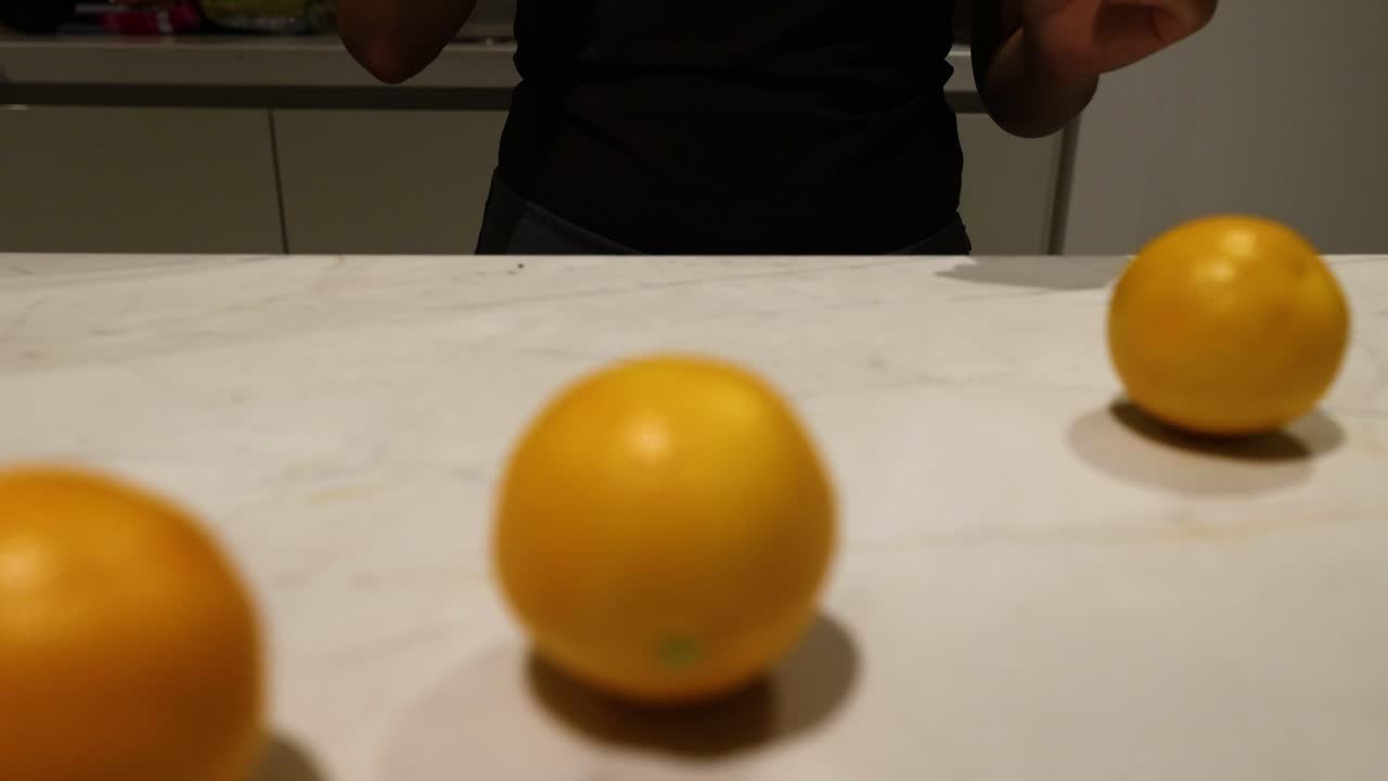 manos empujando naranjas en un mostrador de la cocina