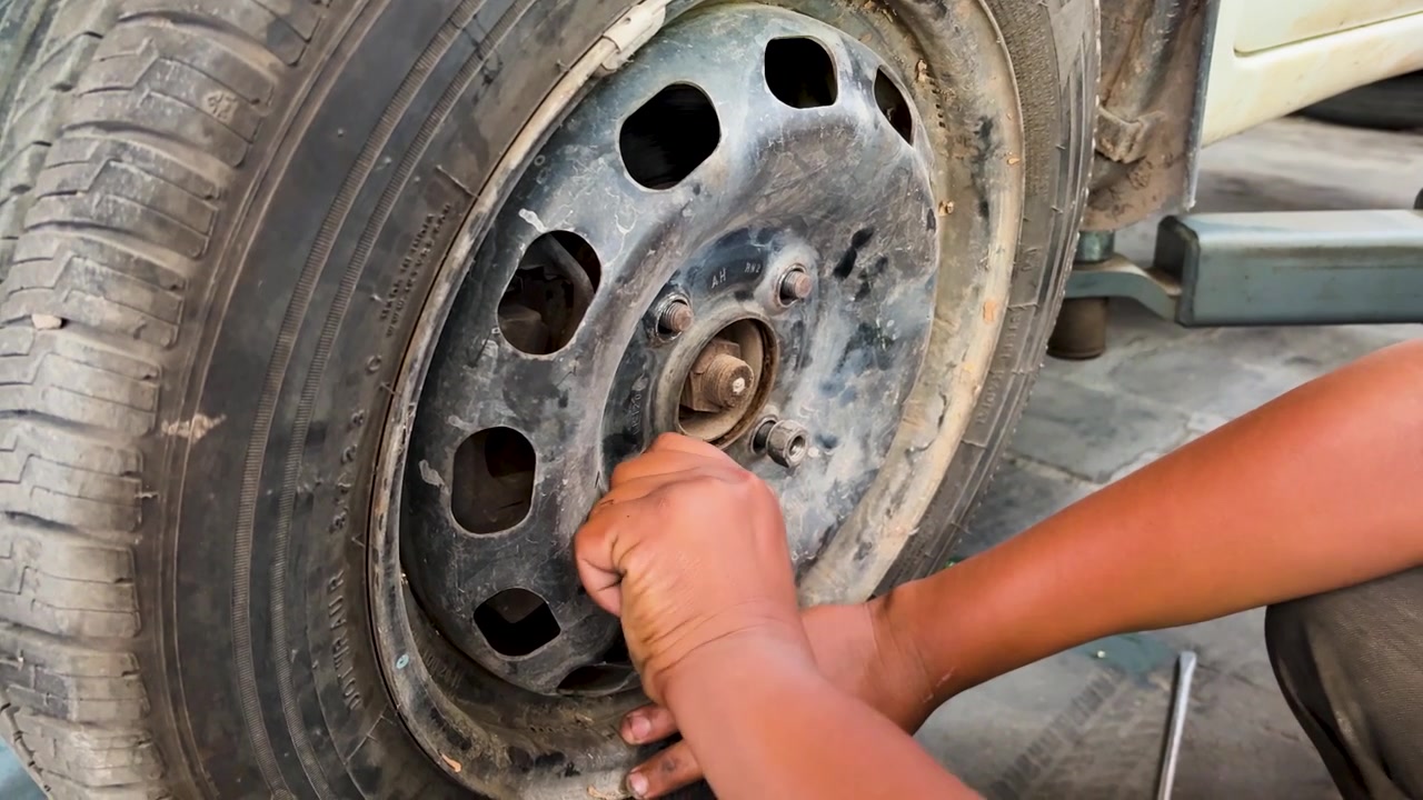 Close Up Of Mechanic Securing Wheel Nuts During Tire Replacement At Auto Workshop