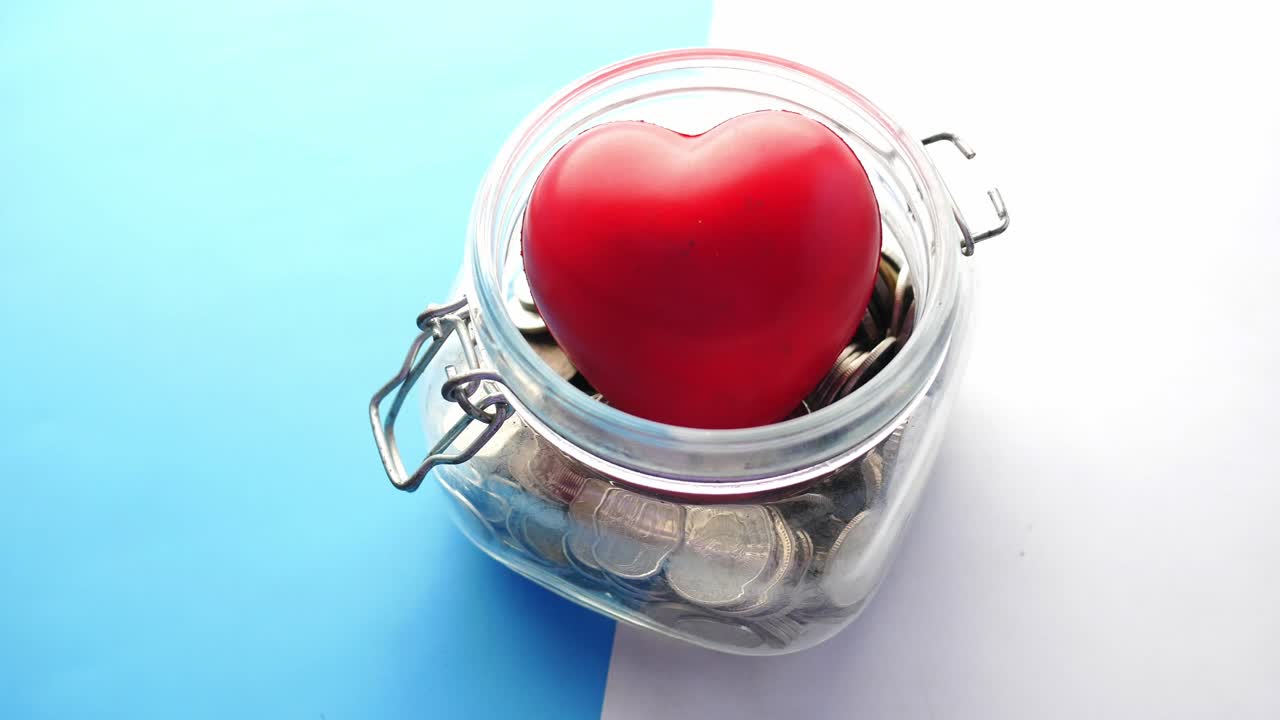 corazón rojo en un frasco de vidrio lleno de monedas