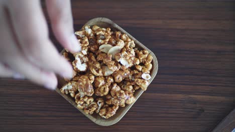 hand picking caramel popcorn with almonds