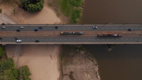 Aerial-birds-eye-overhead-top-down-view-of-traffic-on-road-bridge-and-surrounding-intersection.-Tracking-on-tram-passing-by-another-one.-Warsaw,-Poland