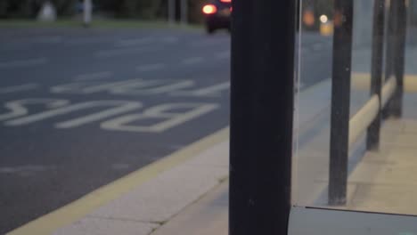 Point-of-view-of-urban-city,-traffic-at-dusk-through-bus-stop-windows