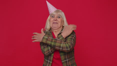 mujer mayor alegre positiva en cono sombrero festivo, bailando, divirtiéndose, celebrando la fiesta de cumpleaños