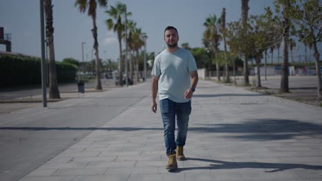 man walking on a city street with palm trees