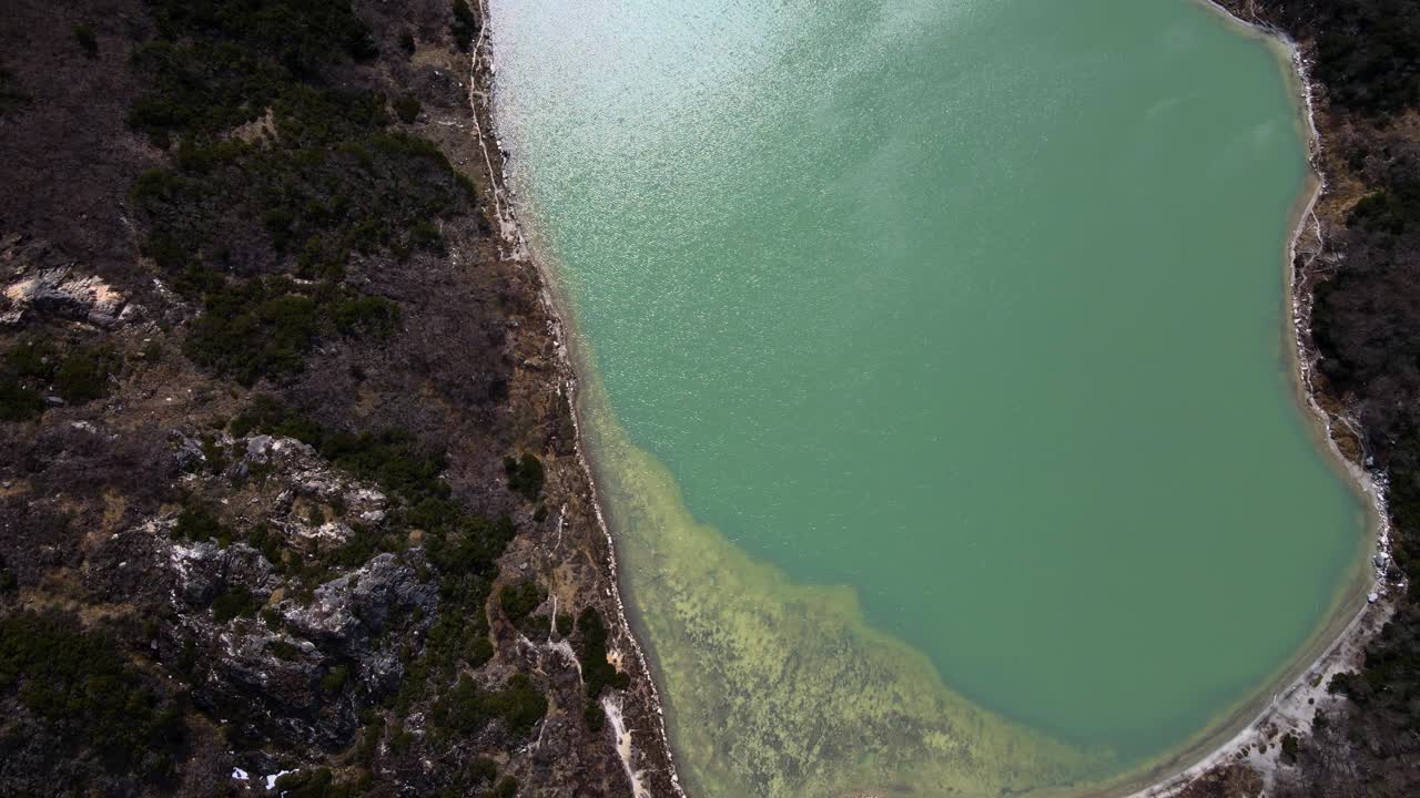 drone de arriba hacia abajo toma panorámica mientras vuela sobre la laguna esmeralda para revelar las montañas cubiertas de nieve de los andes cerca de ushuaia, argentina
