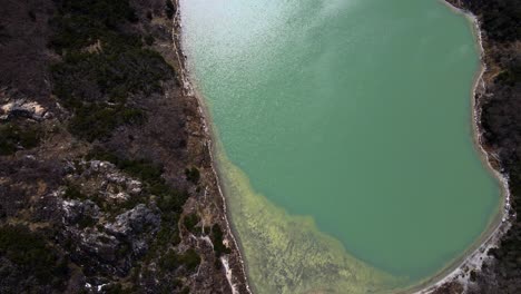 Von-Oben-Nach-Unten-Geschossene-Drohne-Schwenkt-Nach-Oben,-Während-Sie-über-Die-Laguna-Esmeralda-Fliegt,-Um-Die-Schneebedeckten-Anden-In-Der-Nähe-Von-Ushuaia,-Argentinien,-Sichtbar-Zu-Machen