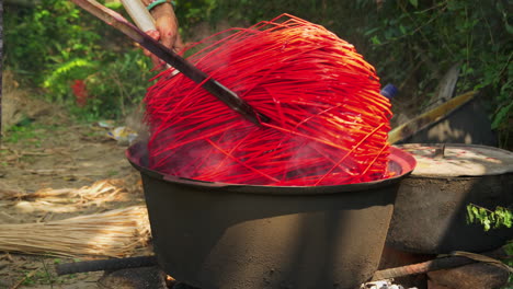 Teñir-Pajitas-De-Rojo-En-Una-Olla-Grande-A-Fuego-Abierto