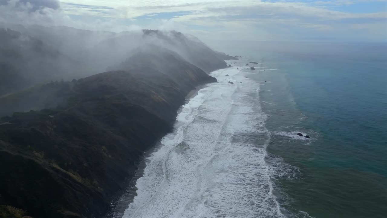 Rugged coastline Lost Coast Trail USAL Beach campground 4wd black sand mist rain fog aerial drone California PNW sun rays waves crashing cloud layer morning Chimney Rocks forward pan up motion