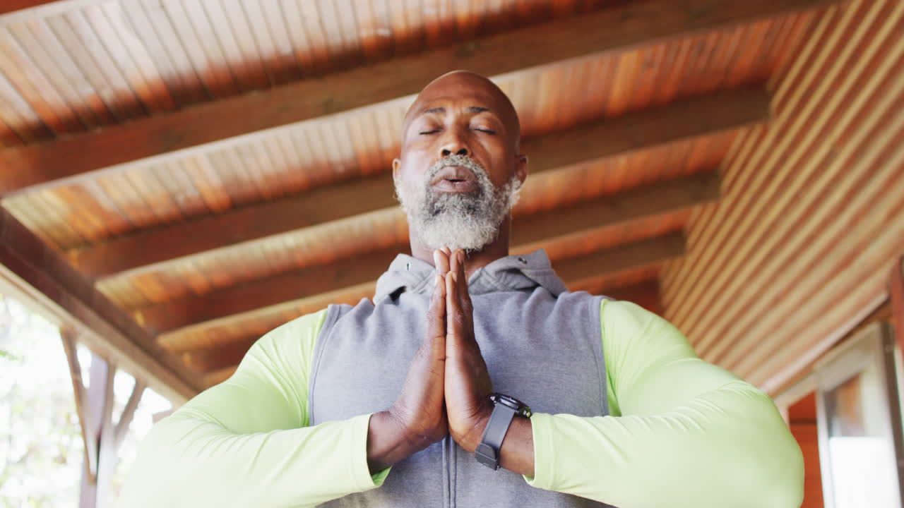 Homme afro-américain âgé pratiquant le yoga dans un chalet
