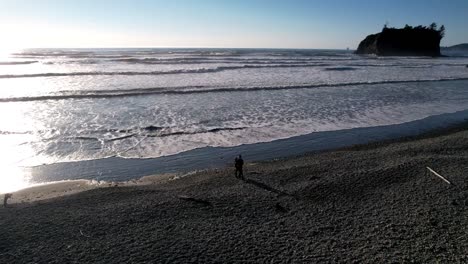 Toma-Aérea-De-Una-Pareja-Parada-Cerca-De-La-Playa-Ruby-Durante-La-Puesta-De-Sol