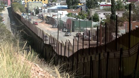 a hillside view front behind a large fence looking down on an intercity street neighborhood