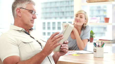 Smiling-casual-colleagues-using-digital-tablet-in-office