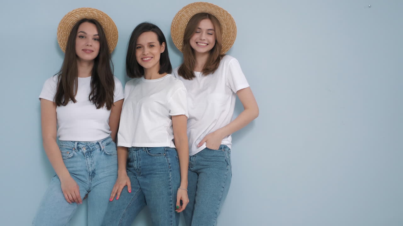 tres amigos felices posando en sombreros de paja y camisetas blancas