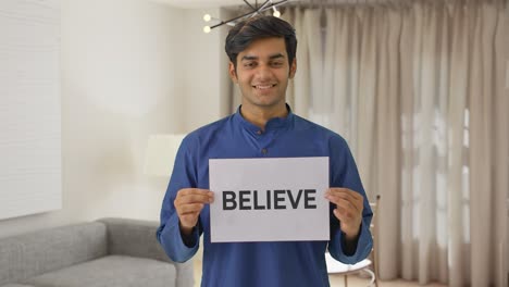 happy indian boy holding believe banner