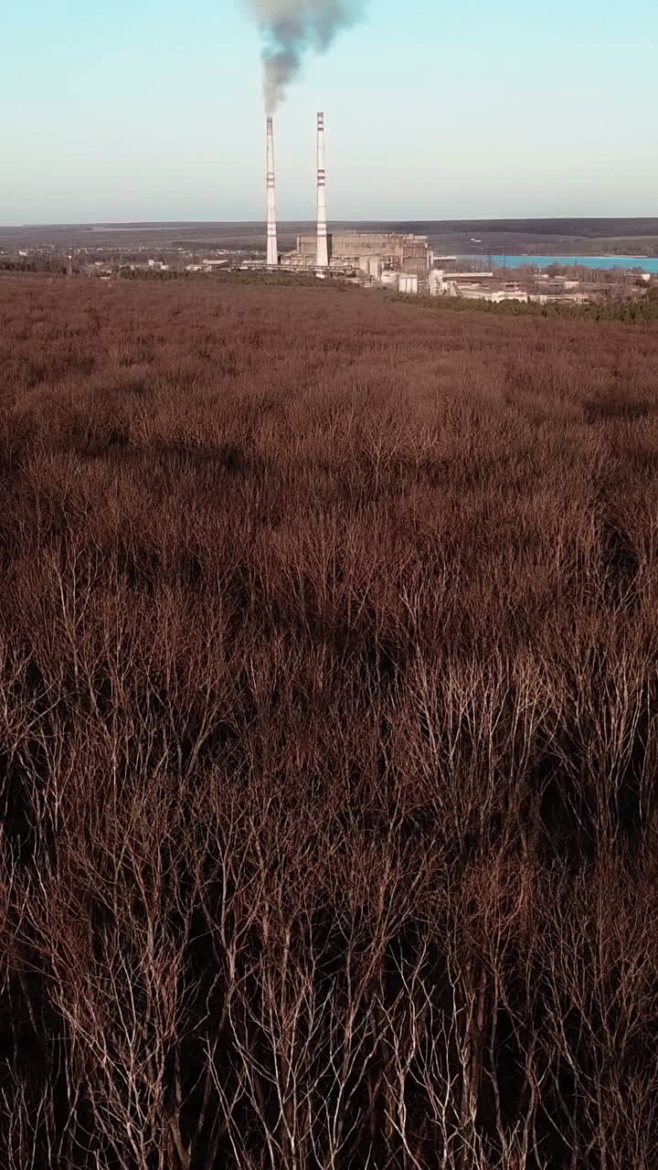 power station is working on the background of the river and the forest in the autumn. Aerial view Vertical video