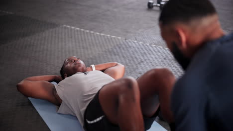 man doing sit-ups with personal trainer