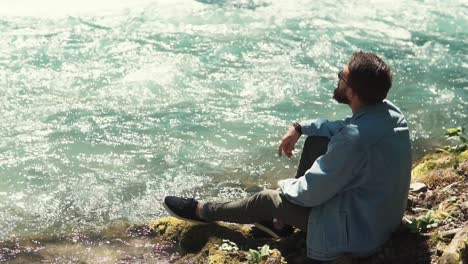 hombre sentado junto a un río