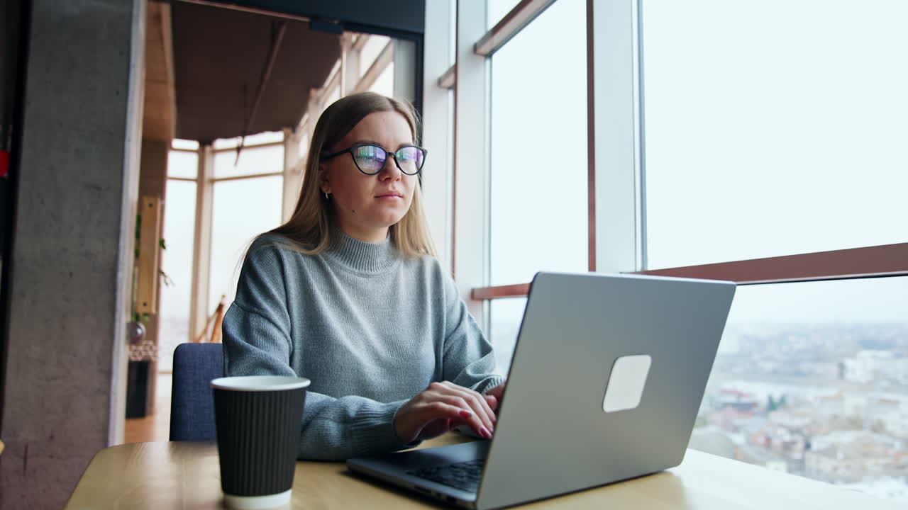 Focused young lady working on her laptop. Entrepreneur has some problem, finds a mistake and looks puzzled. Low angle view.