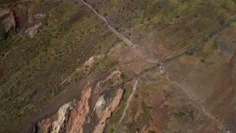 Aerial-view-looking-down-above-tourists-trekking-Ponta-de-sao-Lourenco-scenic-hiking-mountain-slope-path