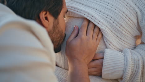 cute husband stroking pregnant woman belly kissing close up. family pregnancy