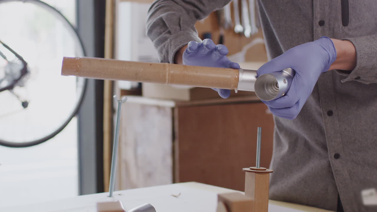 primer plano de un artesano masculino en un taller de montaje de un marco de bicicleta de bambú sostenible construido a mano